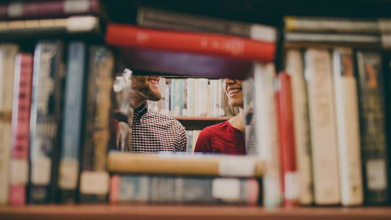 man and woman in the library smiles to each other
