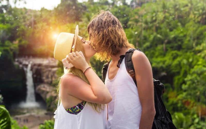 Hombre y mujer besándose en la naturaleza con hermosa luz del sol