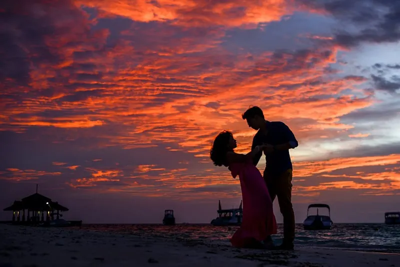 man and woman on beach dancing during the sunset