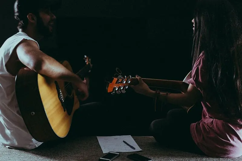 man and woman playing guitar in dark place