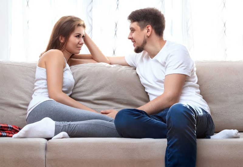man and young woman talking on couch