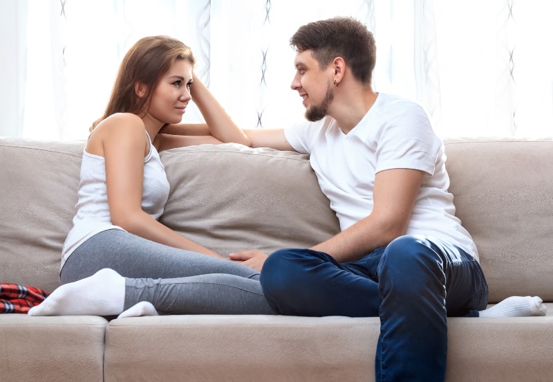 hombre y mujer joven hablando en el sofá