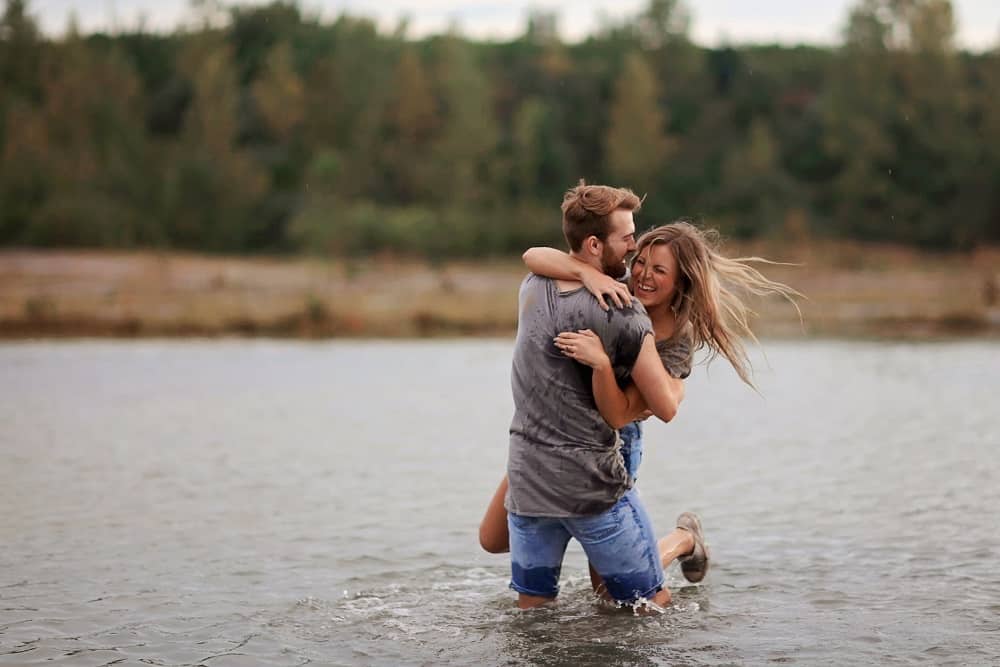 man hugging woman while standing in the body of water