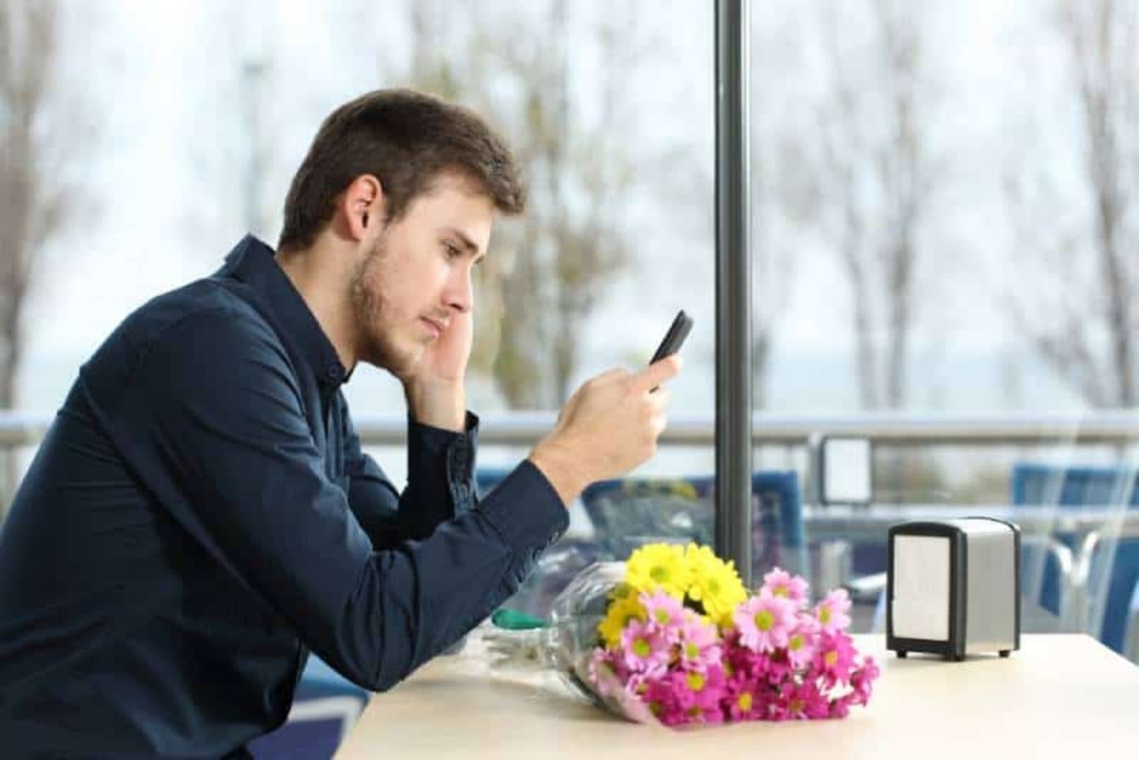 uomo che guarda il telefono infelice