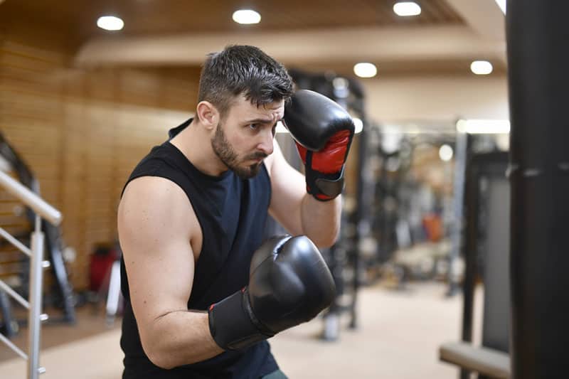man on boxing gloves boxing inside a gym