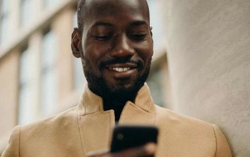 Man smiling and texting on his phone