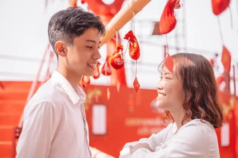 man smiling in front of a woman with orange background and hanging decors around