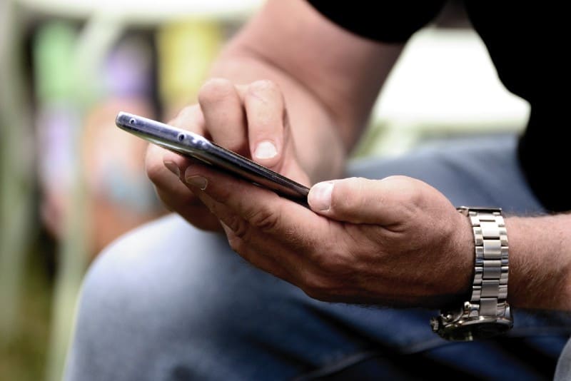 man with watch using mobile phone