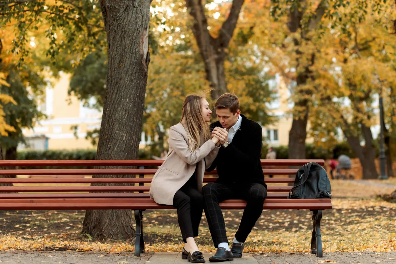 on a park bench a man kisses a woman's hands
