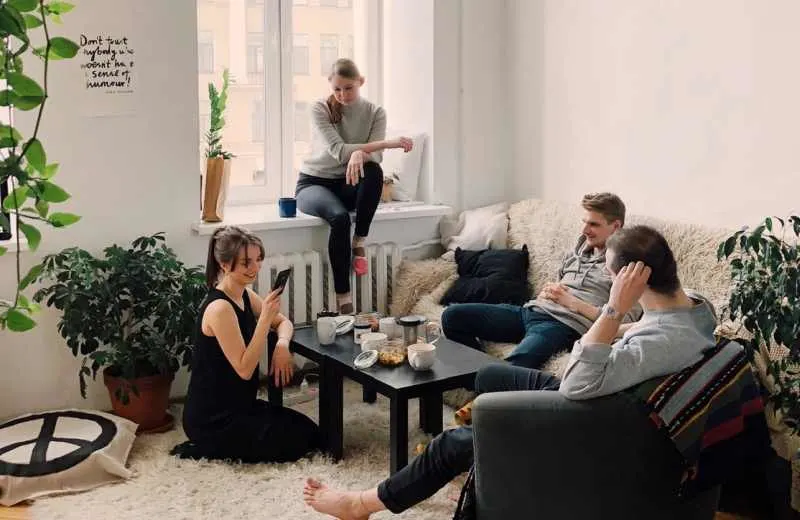 People gathered inside house sitting on sofa and talking to each other