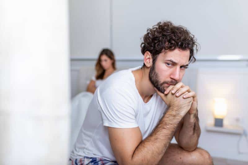 sad man sitting and thinking while his girlfriend is behind him