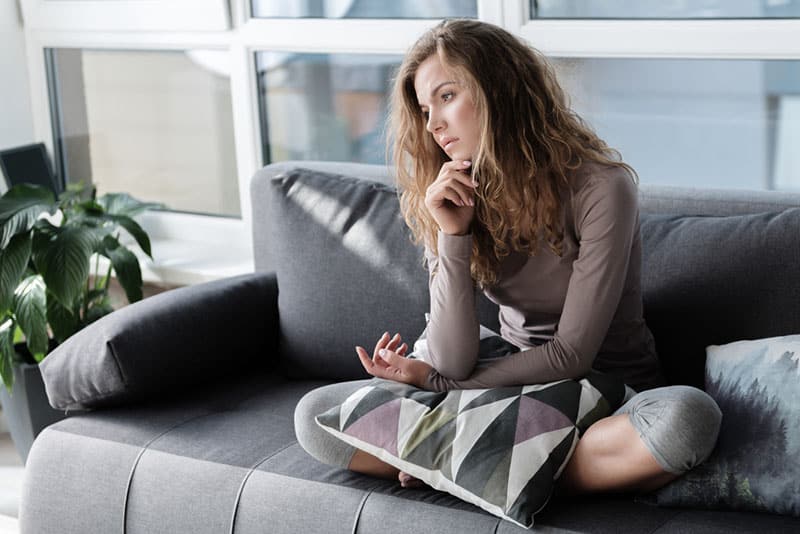 sad mindful woman sitting on the couch