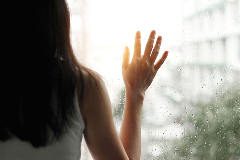 sad woman holding hand on the window
