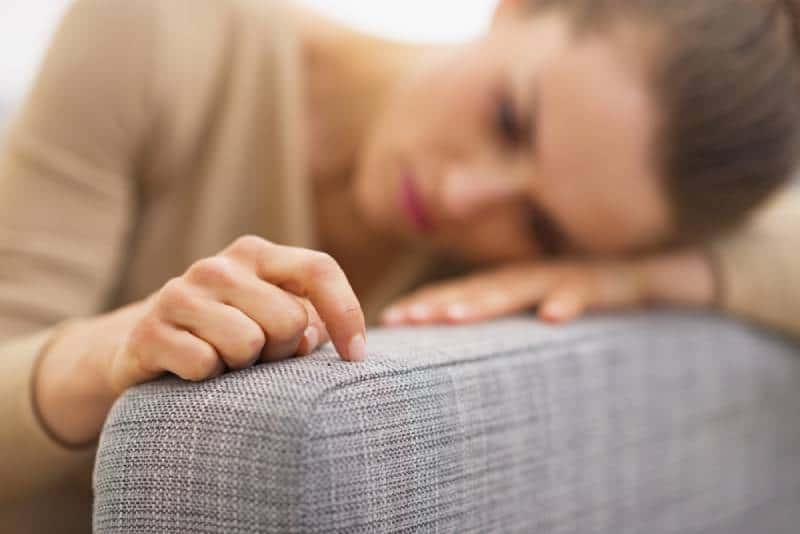sad woman lying in living room and thinking