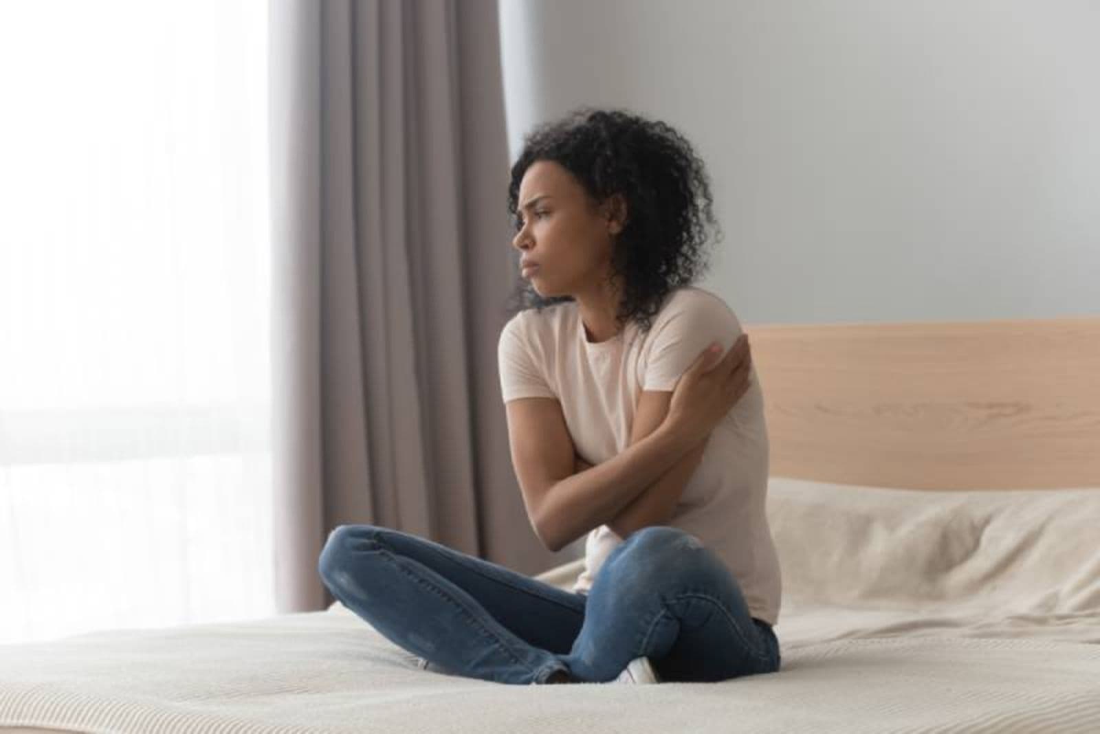 mulher triste sentada na cama em casa sozinha