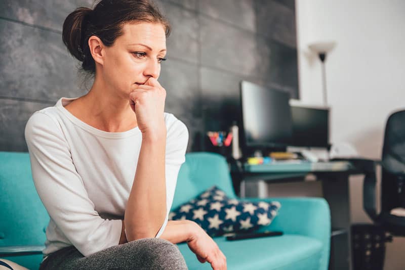 sad woman sitting on the blue couch and thinking