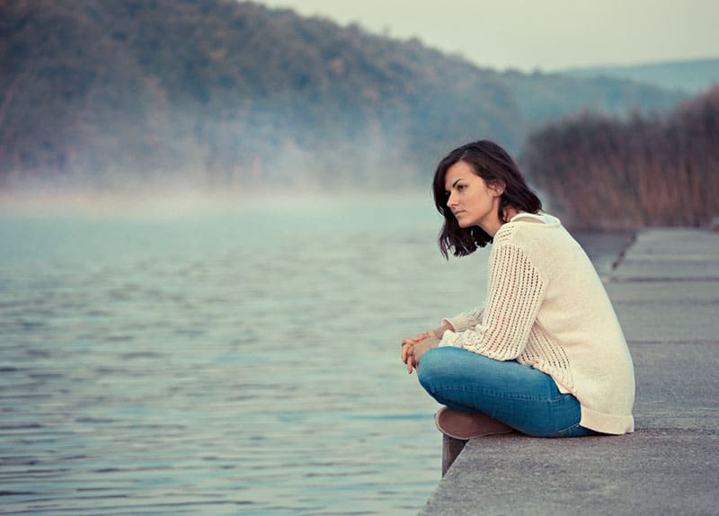 sad young woman by water