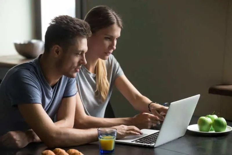 serious couple sitting at home and looking at laptop