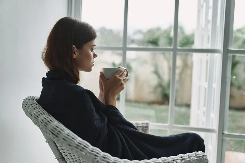 serious woman drinking coffee near the window