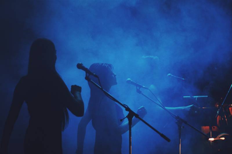silhouette of three women singing in front of crowd