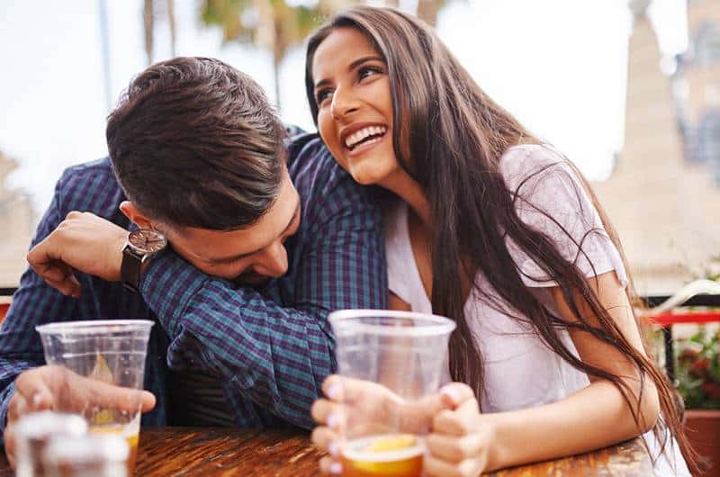 pareja sonriente bebiendo cerveza en vaso de plástico
