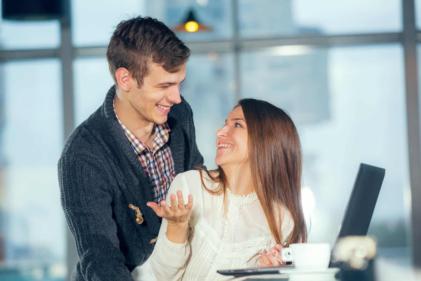 smiling couple in love in a cafe using a laptop