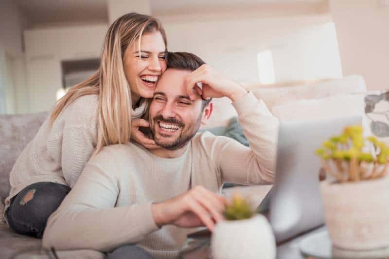 smiling couple working on laptop at home