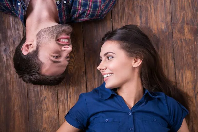 smiling couple lying together on the floor and looking at each other