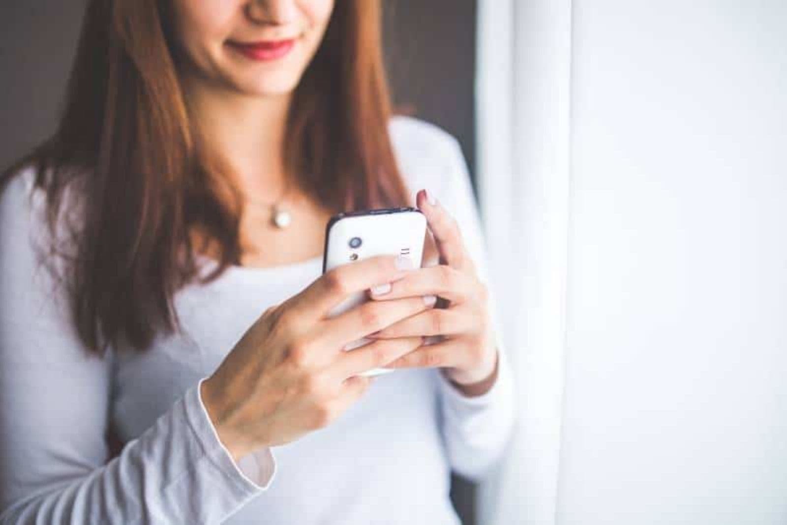 chica sonriente escribiendo sms en casa