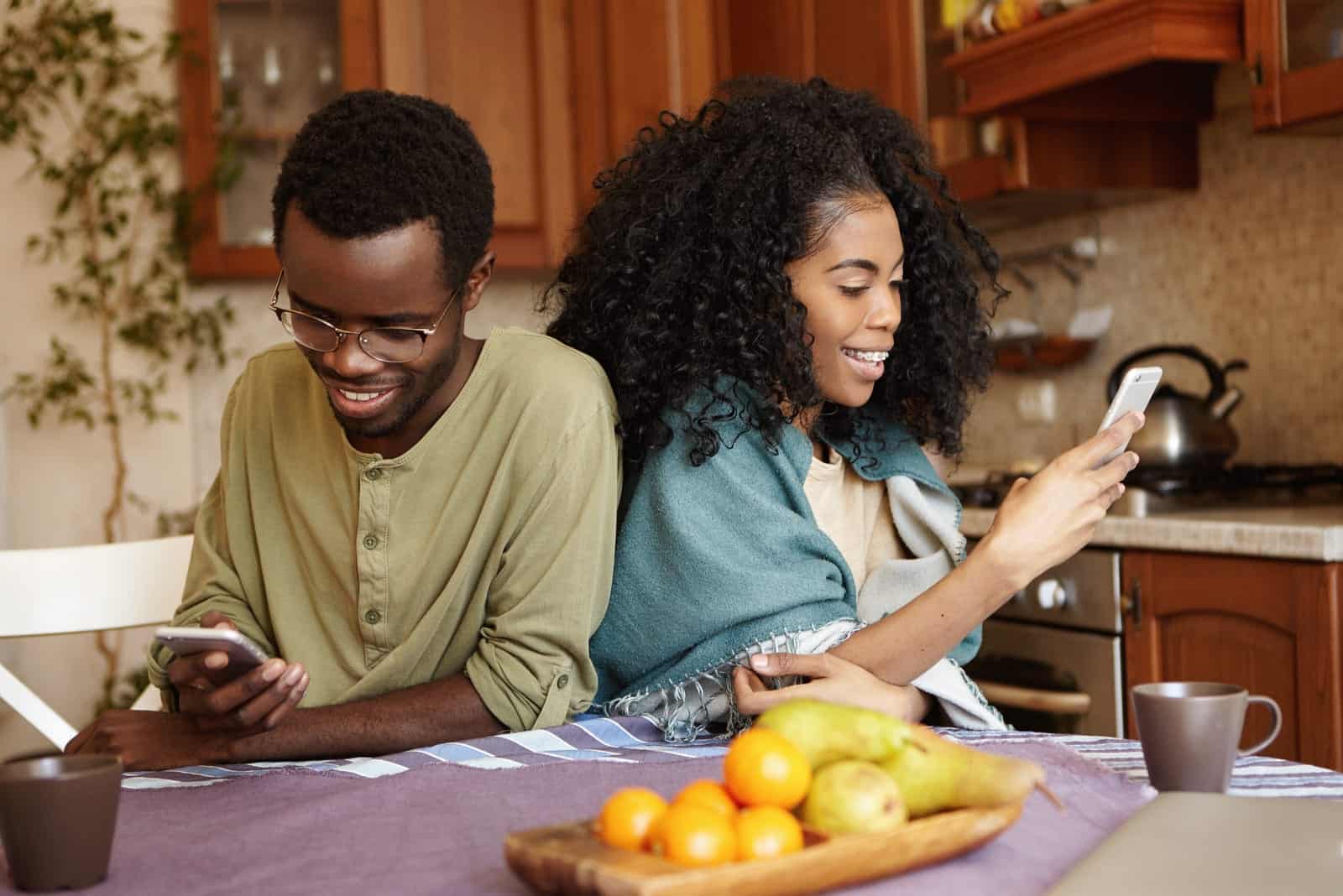 smiling loving couple in the kitchen using smartphones