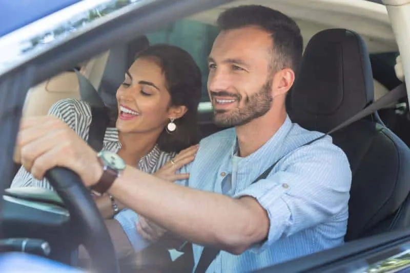 smiling woman hugging her husband while driving car