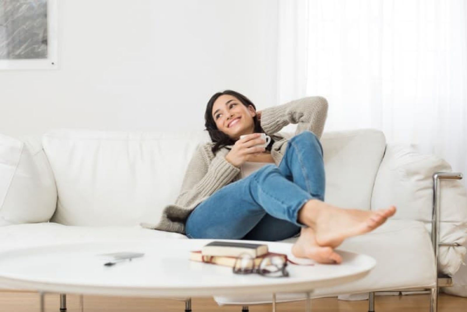 donna sorridente seduta sul divano mentre beve il tè