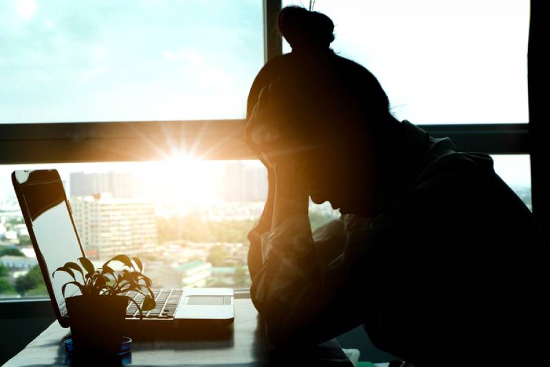 stressed woman holding her head at computer desk