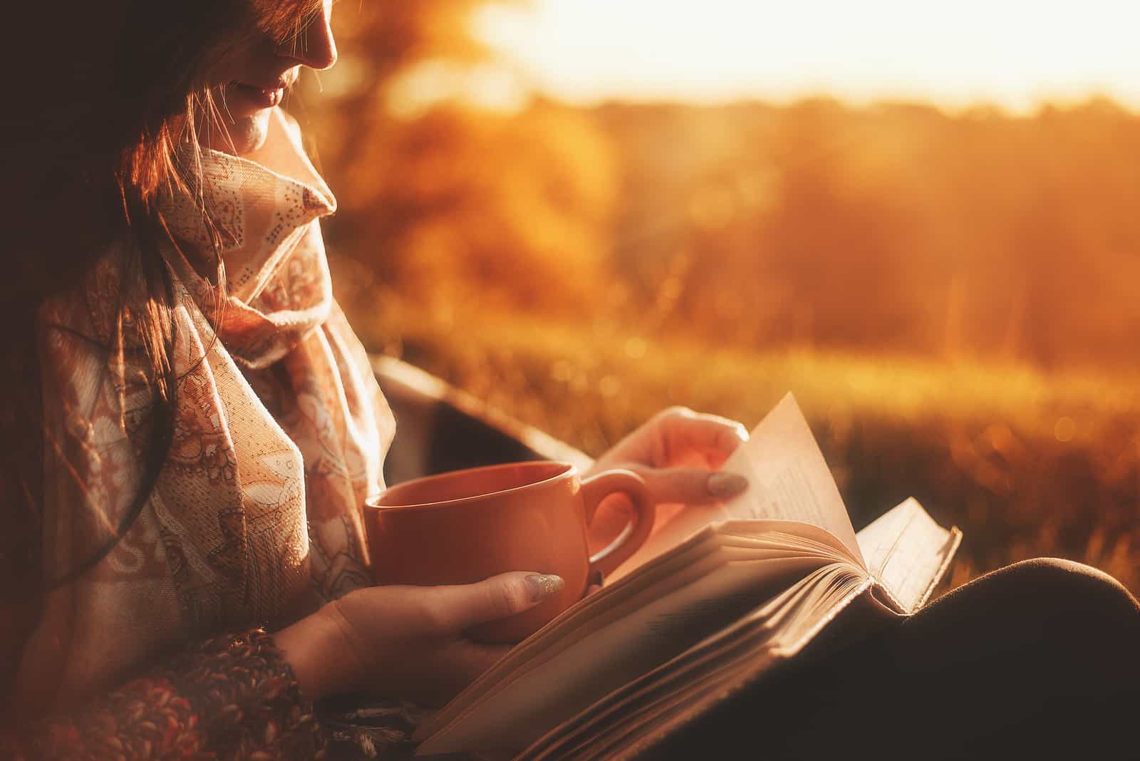 la donna è seduta a bere un caffè e a leggere un libro