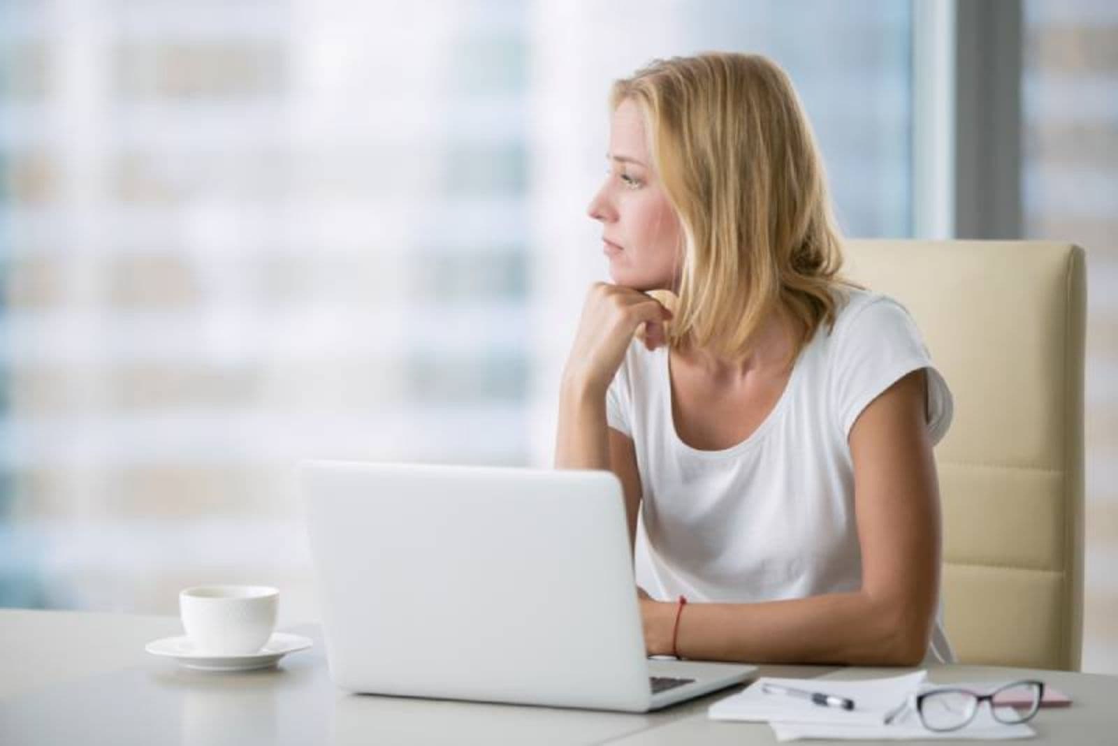 mujer pensante en la oficina mirando al exterior