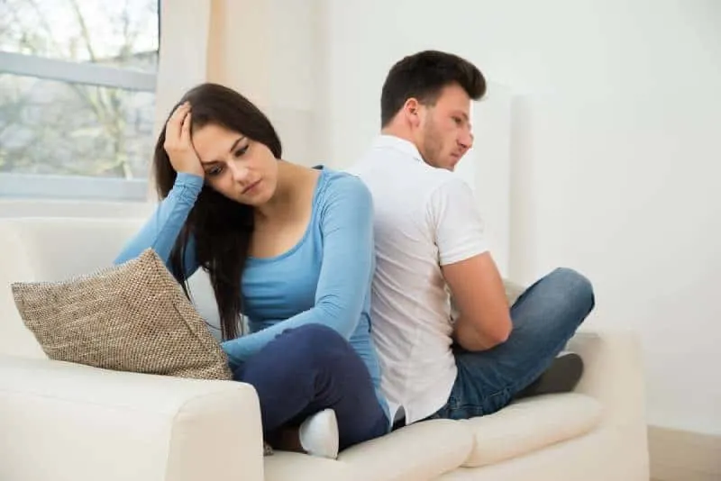 thougtful couple sitting back to back on couch