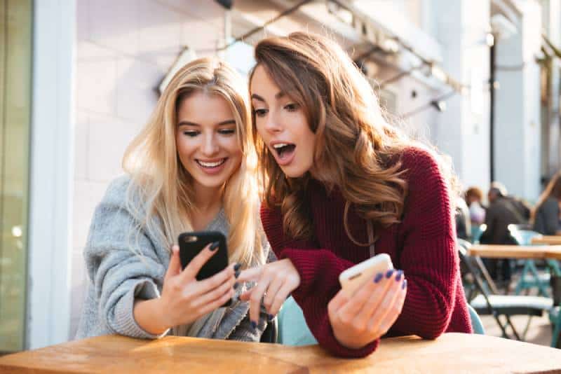 two female friends looking at phone at cafe