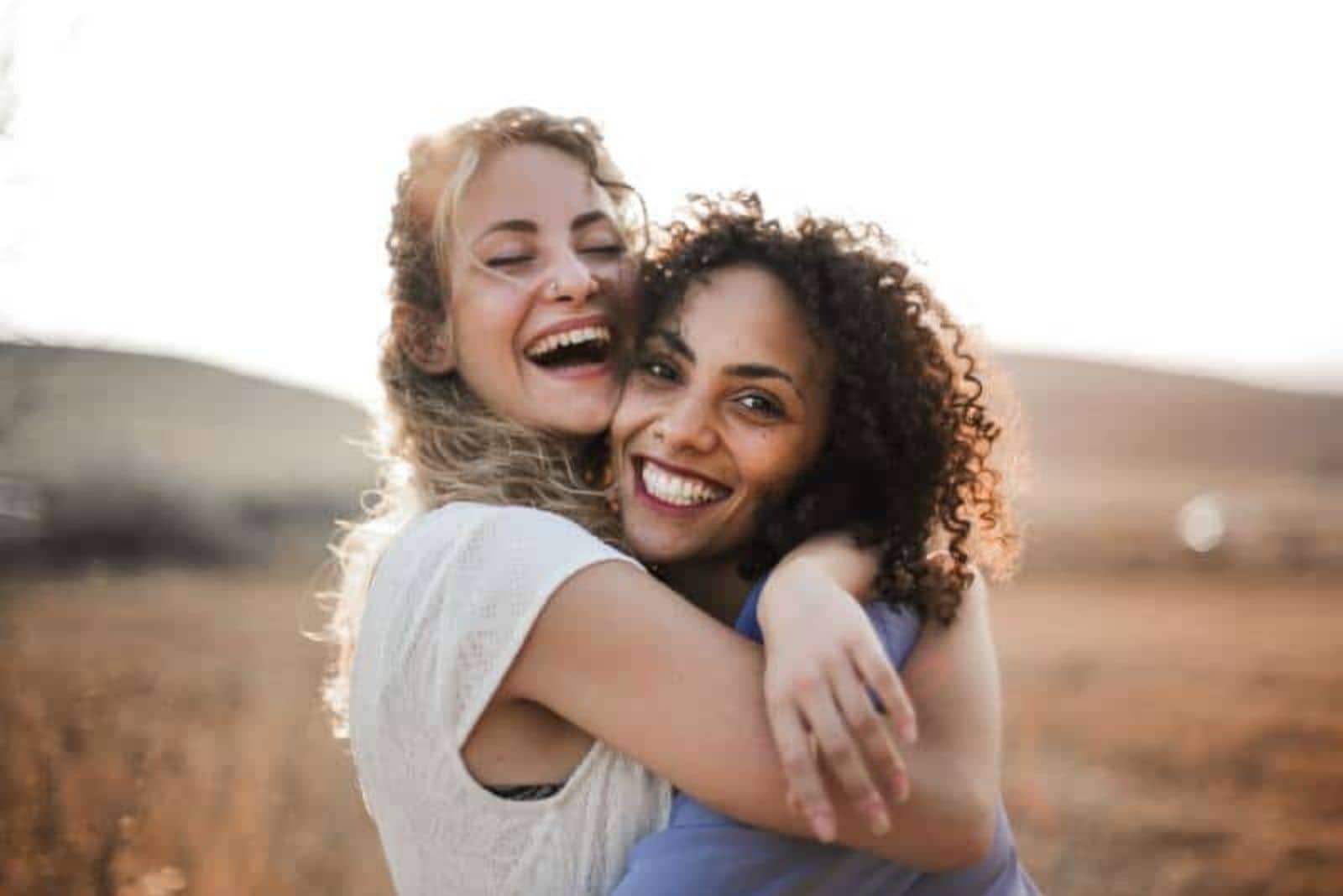 dos amigas sonrientes abrazándose al aire libre