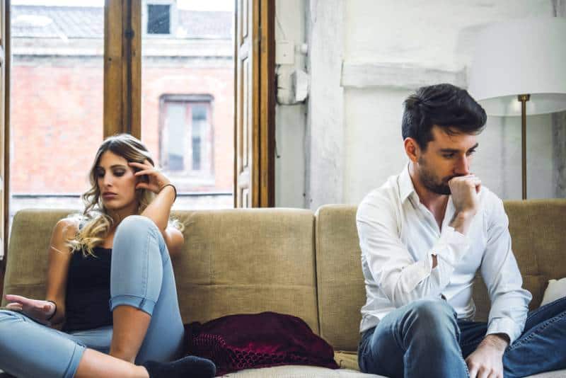 unhappy couple sitting on couch at home