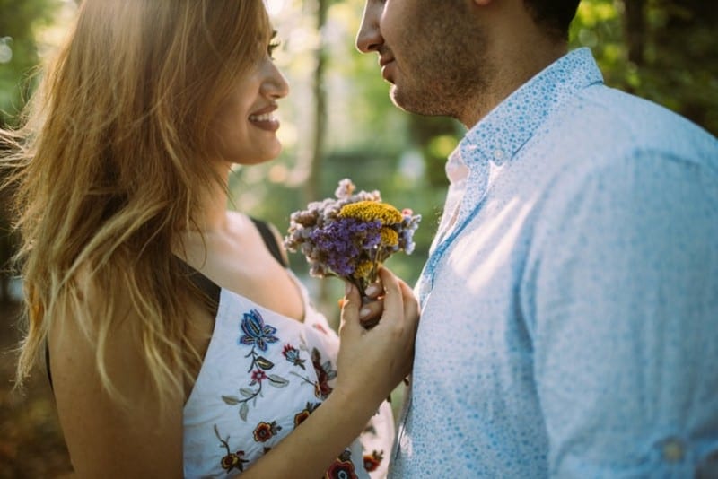 Uomo e donna rivolti l'uno verso l'altra mentre tengono in mano dei fiori