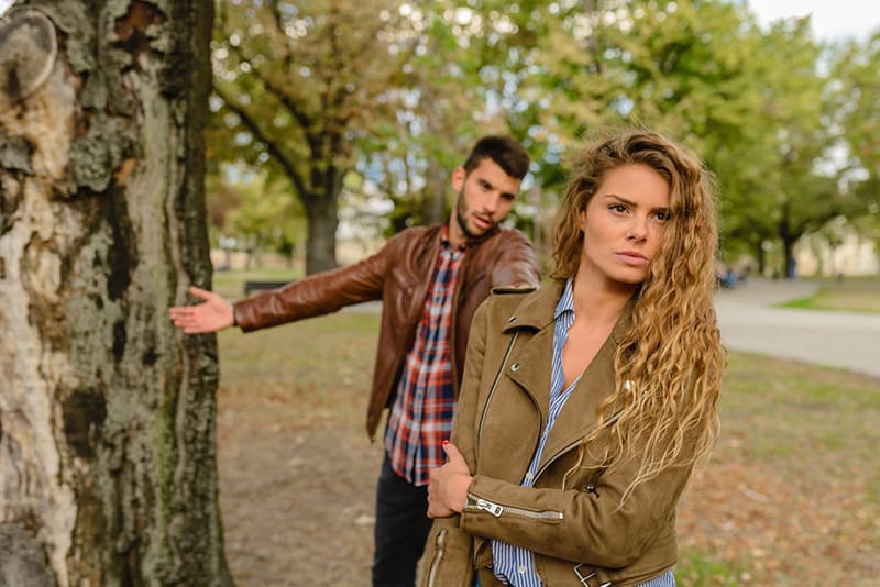woman and man standing near tree in the park and arguing