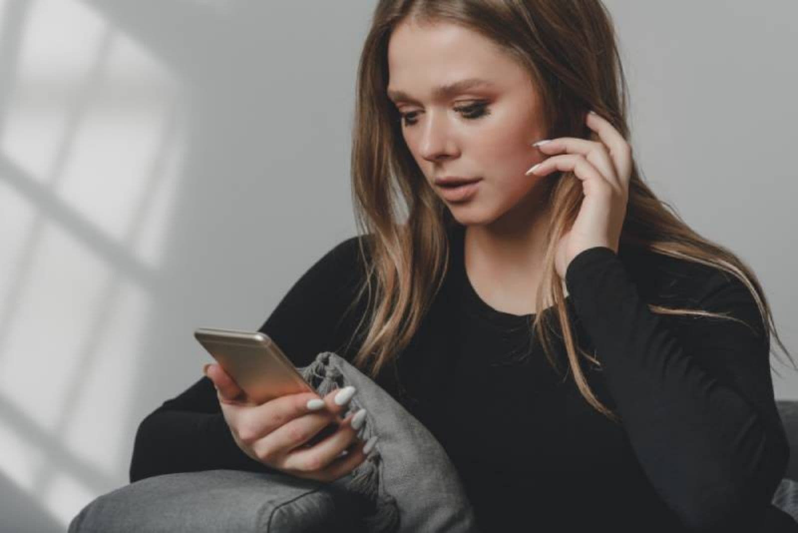 mujer en casa mirando confusa su teléfono