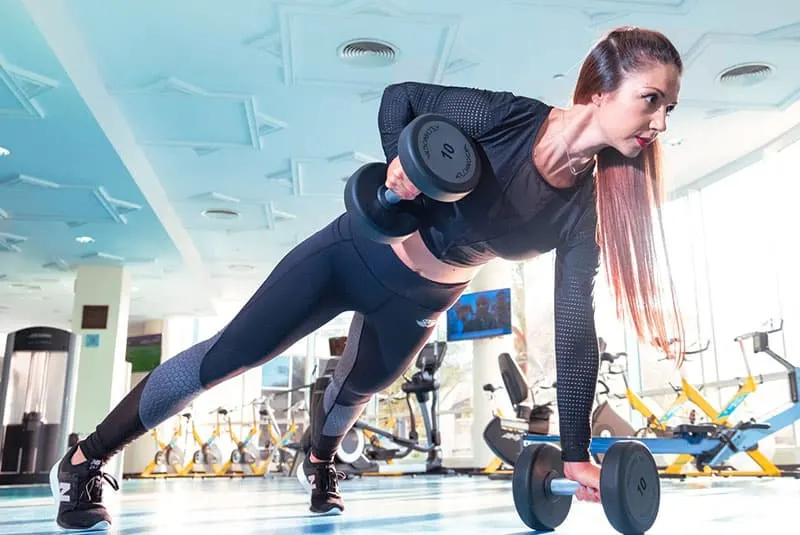 woman exercising in the gym using barbells