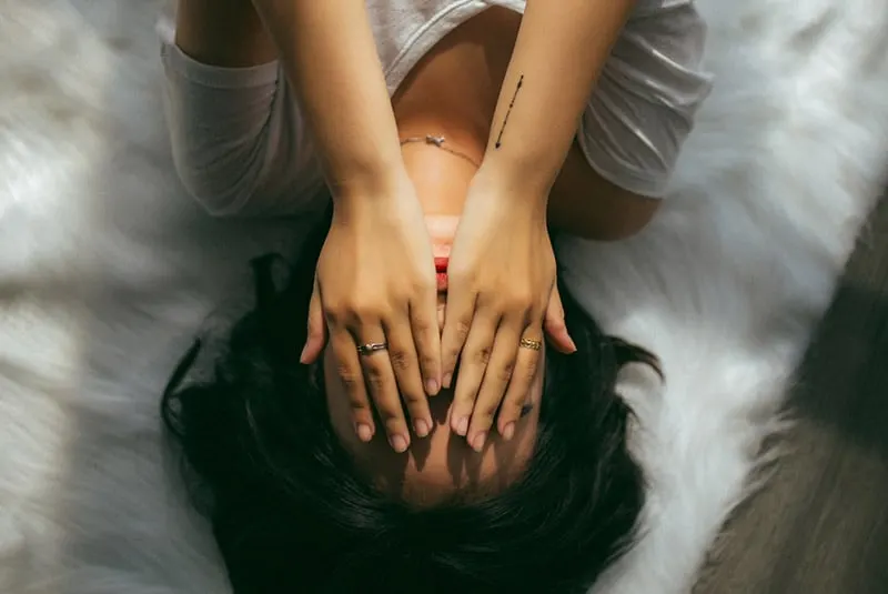 Woman in bed hands covering face