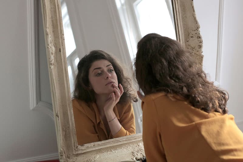 mujer-en-amarillo-camisa-de-mangas-largas-en-frente-de-un-espejo