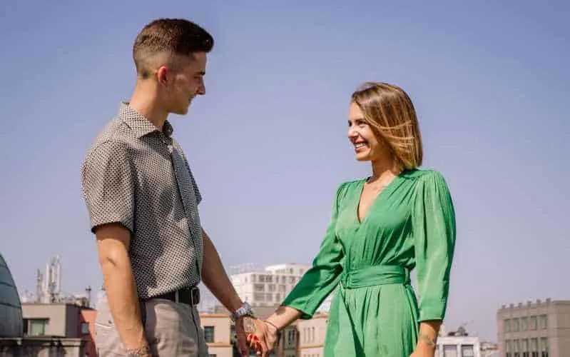 Woman in green dress holding hands with young man