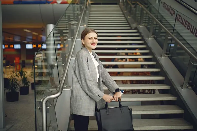 woman inside the airport by the stairs carrying bag