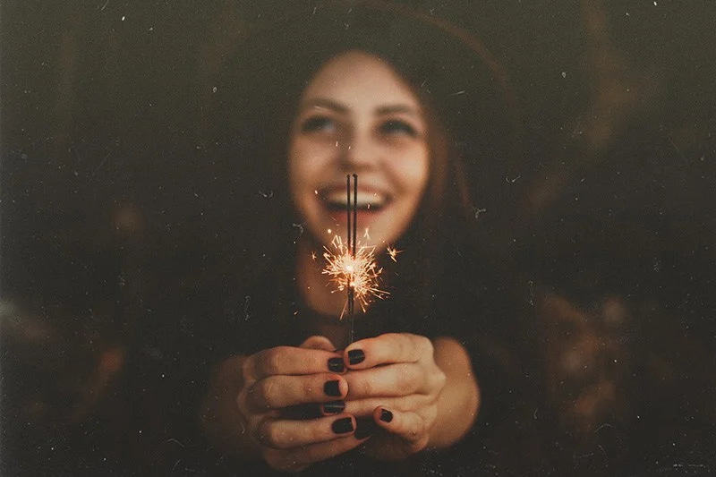 Woman laughing while holding lit sparklers