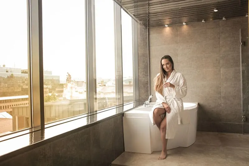 woman on white bathtub and white batchrobe