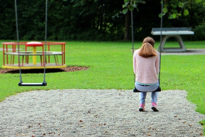 Mujer joven sentada en un columpio en un parque infantil